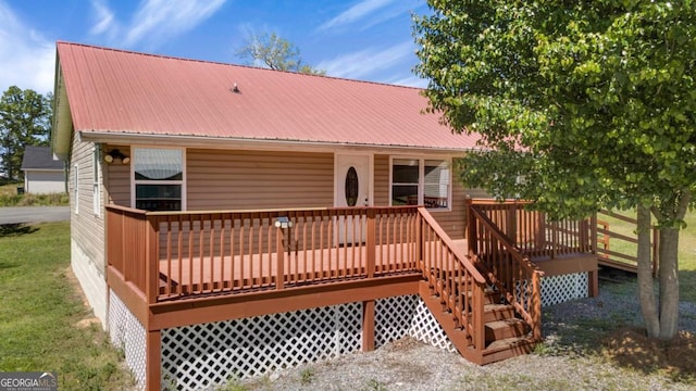 rear view of property featuring metal roof and a wooden deck