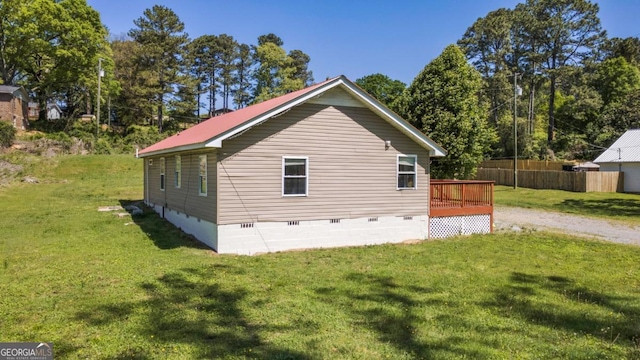 view of property exterior featuring crawl space, fence, a wooden deck, and a lawn