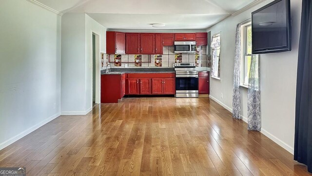 kitchen with a sink, reddish brown cabinets, appliances with stainless steel finishes, and wood finished floors