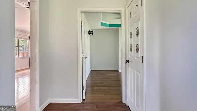 corridor featuring crown molding, baseboards, and wood finished floors