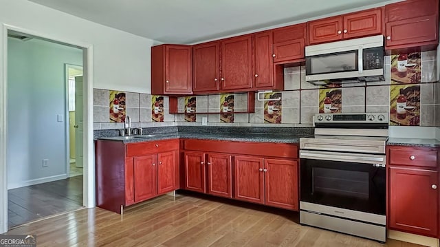 kitchen featuring a sink, appliances with stainless steel finishes, dark brown cabinets, light wood finished floors, and decorative backsplash