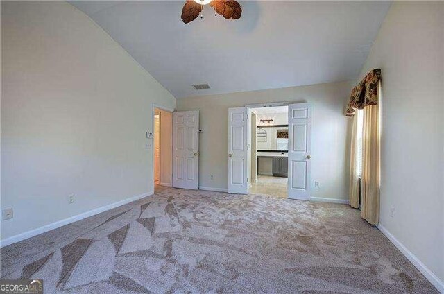 unfurnished bedroom with baseboards, vaulted ceiling, carpet floors, visible vents, and ceiling fan