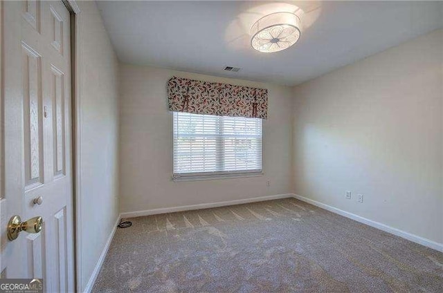 carpeted spare room featuring visible vents and baseboards