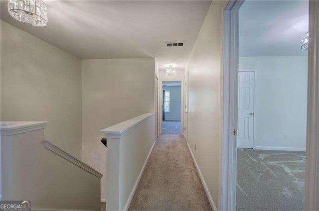 corridor with visible vents, baseboards, an upstairs landing, and carpet floors
