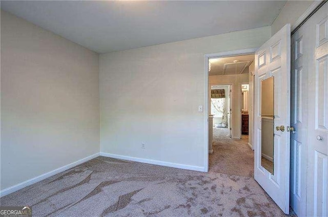 carpeted spare room with attic access and baseboards