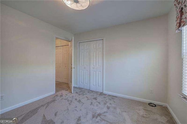 unfurnished bedroom with carpet floors, baseboards, and a closet