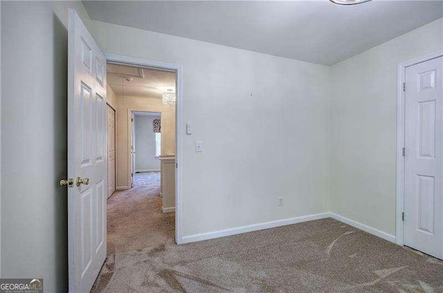 carpeted empty room with baseboards and attic access