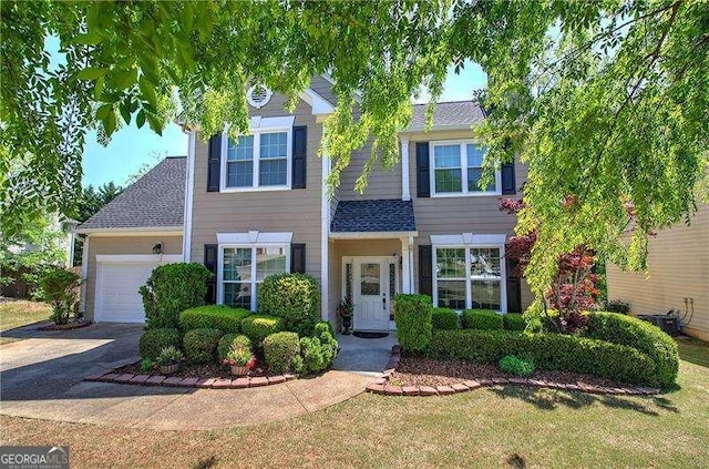 colonial-style house with a garage, a front yard, roof with shingles, and driveway