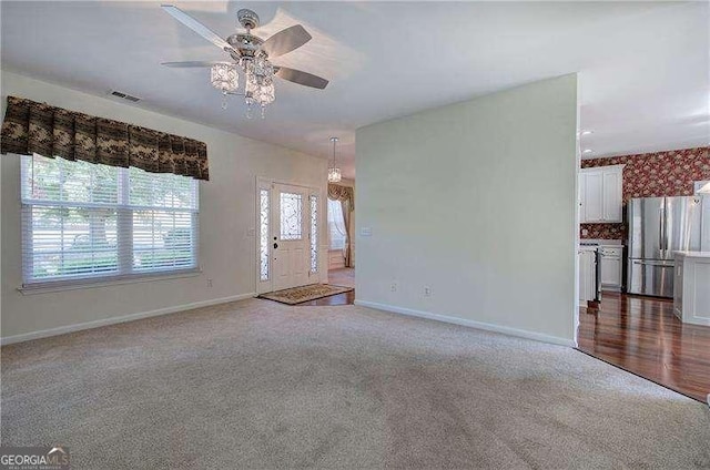 unfurnished living room with visible vents, ceiling fan, baseboards, and carpet floors