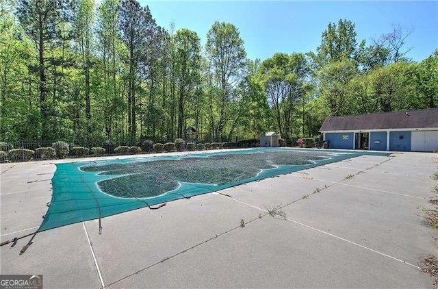 pool featuring an outbuilding, a patio area, and fence