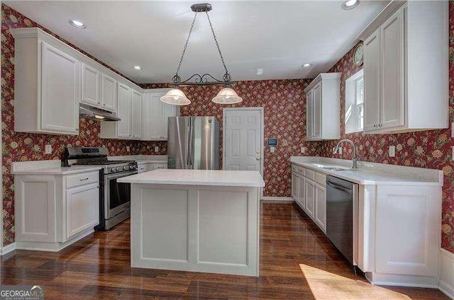 kitchen featuring a sink, appliances with stainless steel finishes, under cabinet range hood, and wallpapered walls