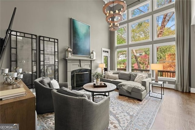 3749 Watkins Pl NE, Brookhaven, GA 30319 - living room featuring a towering ceiling, a chandelier, a fireplace, and wood finished floors