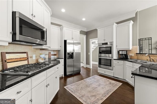 3749 Watkins Pl NE, Brookhaven, GA 30319 - kitchen with appliances with stainless steel finishes, a sink, white cabinets, ornamental molding, and dark wood finished floors