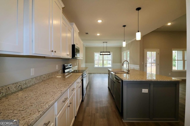 kitchen with dark wood-style floors, white cabinets, wainscoting, appliances with stainless steel finishes, and a sink
