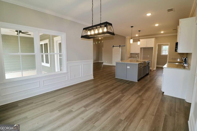 kitchen with white cabinetry, a sink, ornamental molding, and a barn door