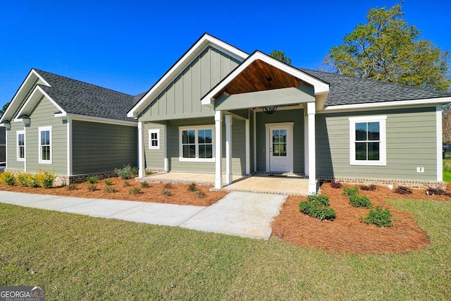 craftsman house with a shingled roof, board and batten siding, and a front lawn