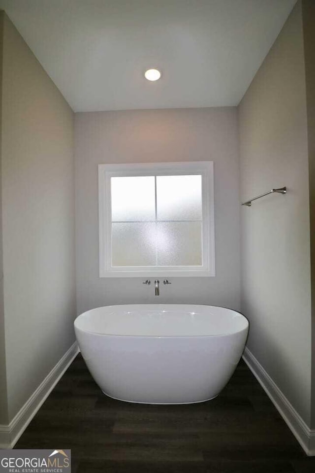 bathroom with recessed lighting, baseboards, a freestanding bath, and wood finished floors