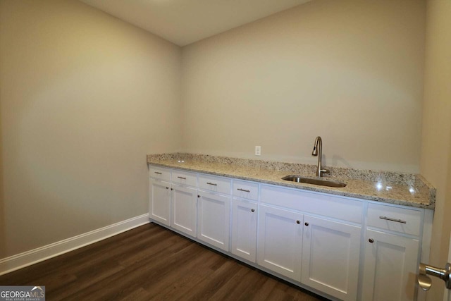interior space with dark wood-type flooring, a sink, and baseboards