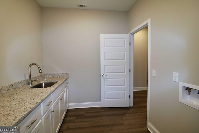 washroom with hookup for a washing machine, dark wood-type flooring, visible vents, a sink, and baseboards