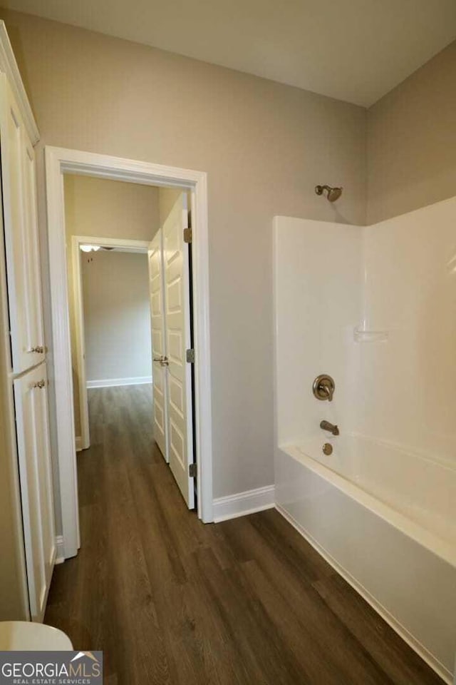 full bath featuring bathing tub / shower combination, wood finished floors, and baseboards