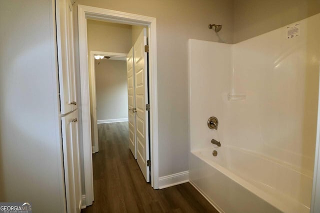 bathroom featuring baseboards, bathing tub / shower combination, and wood finished floors