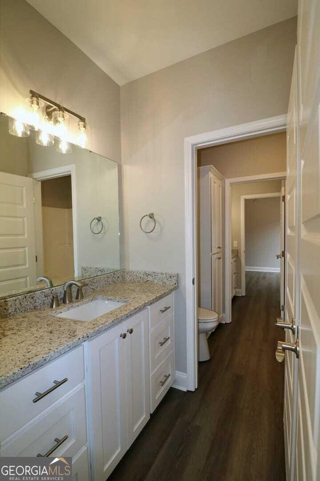 bathroom with toilet, vanity, and wood finished floors