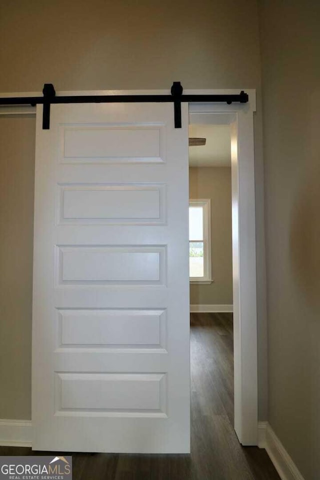 interior details featuring a barn door, baseboards, and wood finished floors