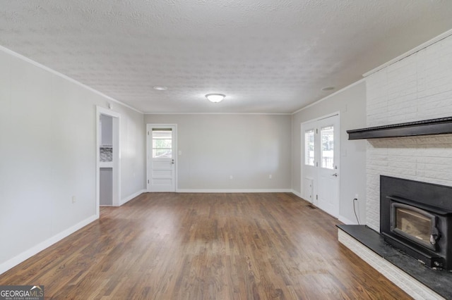 unfurnished living room featuring a wealth of natural light, wood finished floors, crown molding, and baseboards
