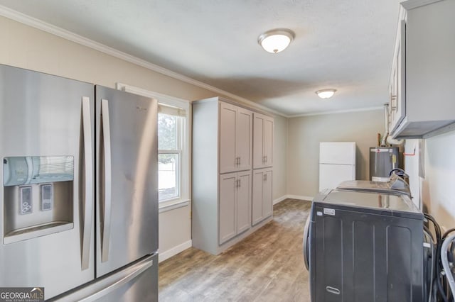 washroom featuring light wood finished floors, laundry area, water heater, washer / clothes dryer, and ornamental molding