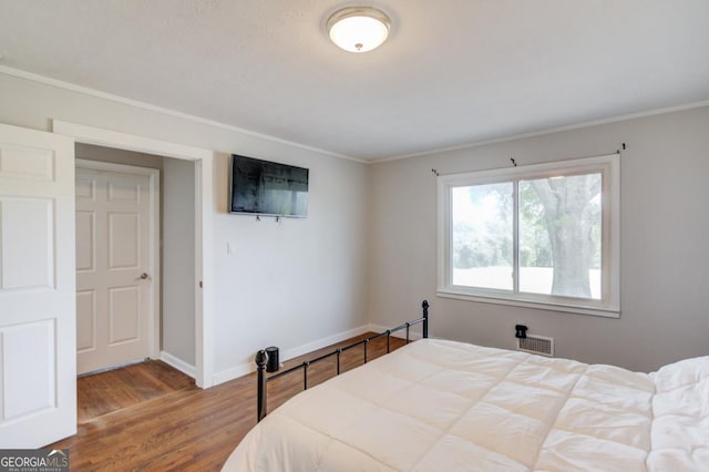 bedroom featuring crown molding, visible vents, wood finished floors, and baseboards