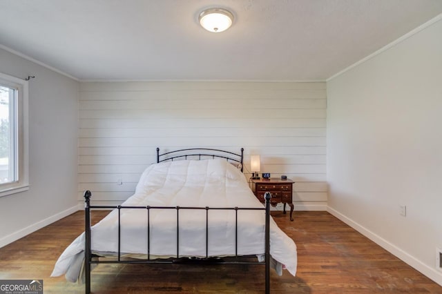 bedroom with ornamental molding, wood finished floors, and baseboards