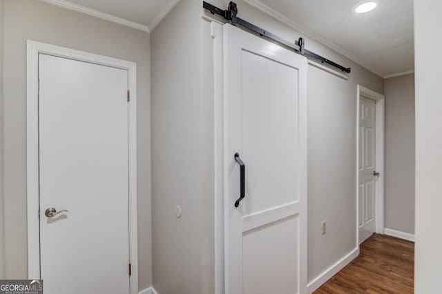 hallway featuring crown molding, wood finished floors, a barn door, and baseboards
