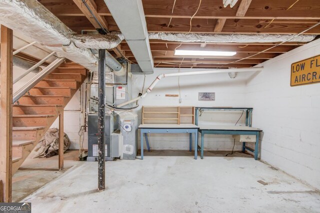unfinished basement featuring stairway and heating unit