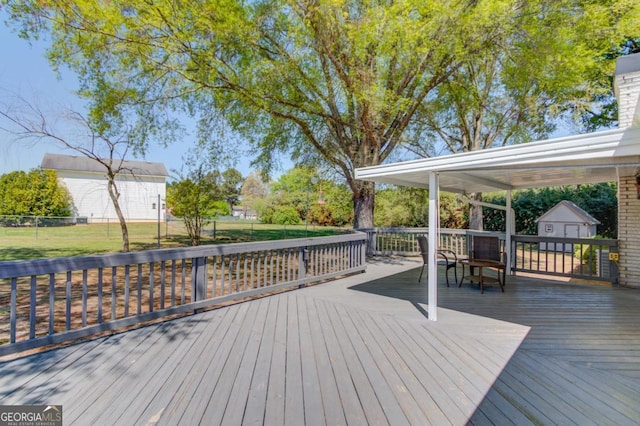 wooden deck with a storage unit, fence, and an outdoor structure