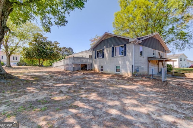 back of property with fence, a wooden deck, and brick siding