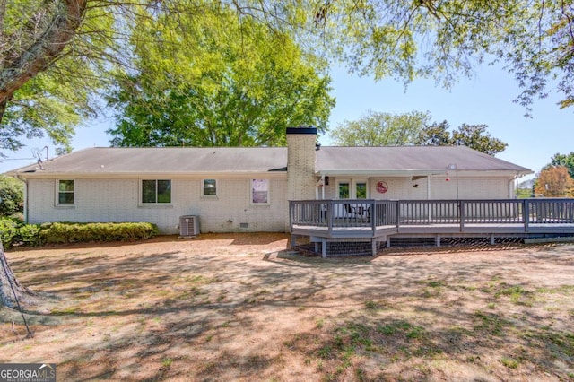 back of property with a wooden deck, crawl space, central AC unit, a chimney, and brick siding