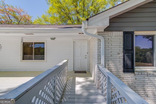 view of exterior entry featuring a deck and brick siding