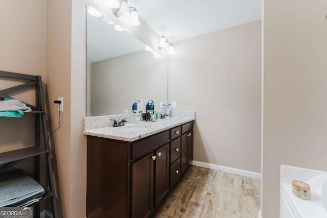 204 Arapahoe Ct, Villa Rica, GA 30180 - bathroom with double vanity, wood finished floors, baseboards, and a sink