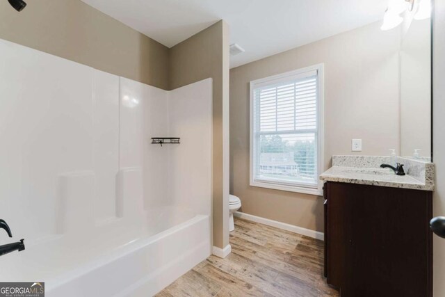 204 Arapahoe Ct, Villa Rica, GA 30180 - bathroom featuring wood finished floors, toilet, vanity, baseboards, and bathtub / shower combination