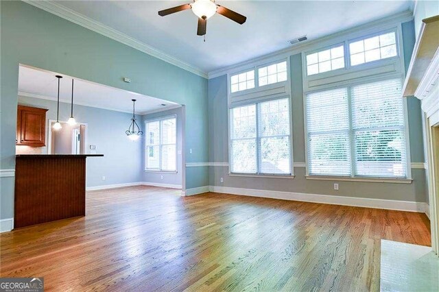 974 Regal Hills Ln, Mableton, GA 30126 - unfurnished living room with ceiling fan with notable chandelier, ornamental molding, visible vents, wood finished floors, and baseboards