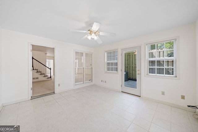 spare room with stairs, a ceiling fan, baseboards, and light tile patterned floors
