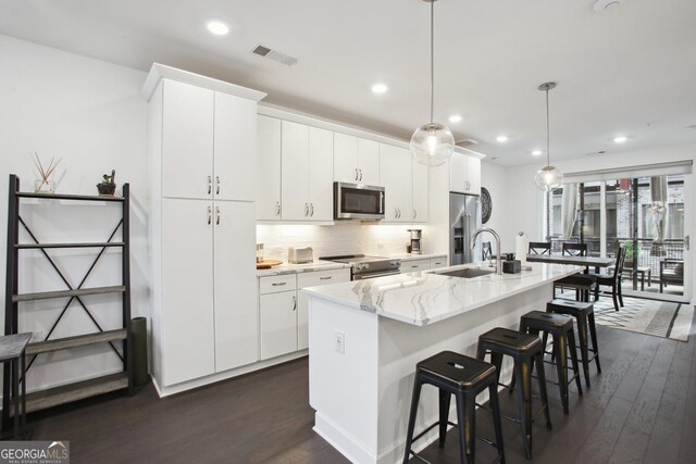 1050 Stacks Ave SE Unit 1507, Atlanta, GA 30315 - kitchen with stainless steel appliances, a sink, dark wood-style floors, an island with sink, and decorative backsplash