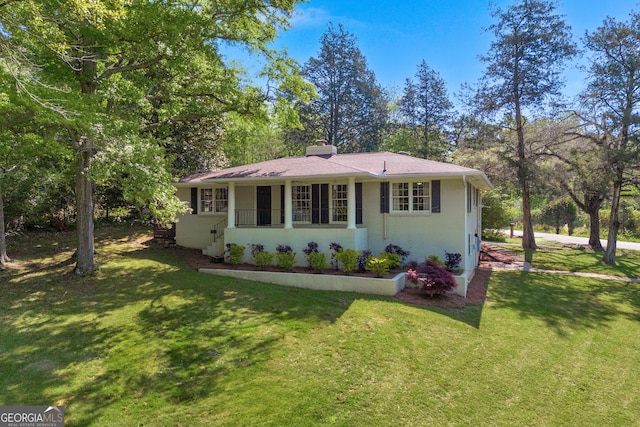 view of front of house featuring a front yard, a chimney, and a shingled roof
