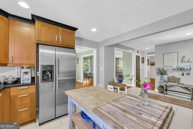 kitchen with light tile patterned floors, brown cabinetry, recessed lighting, and stainless steel fridge