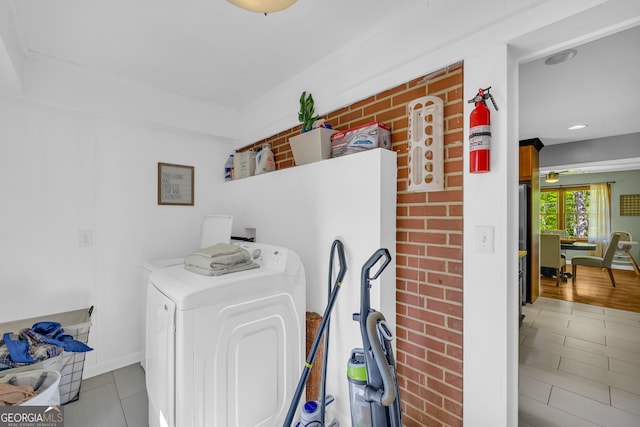 clothes washing area featuring laundry area, brick wall, washer hookup, and tile patterned flooring