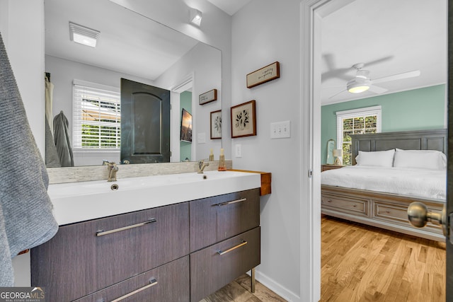 full bath with ceiling fan, double vanity, baseboards, and a healthy amount of sunlight
