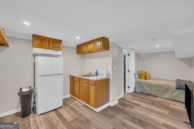 kitchen featuring light wood-style floors, under cabinet range hood, visible vents, and freestanding refrigerator