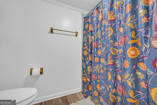 bathroom with baseboards, curtained shower, crown molding, toilet, and wood finished floors