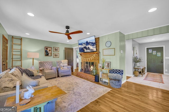 living area with recessed lighting, a brick fireplace, a ceiling fan, and wood finished floors
