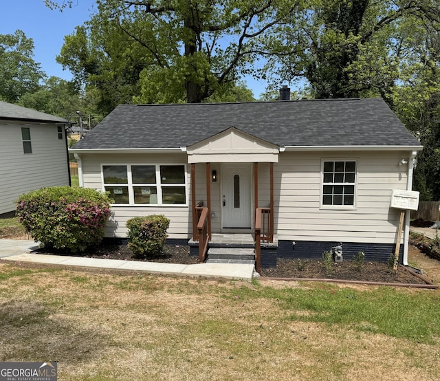 view of front of home with roof with shingles and a front yard